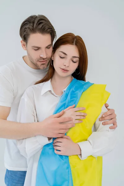 Joven abrazando novia con bandera ucraniana aislada en blanco - foto de stock