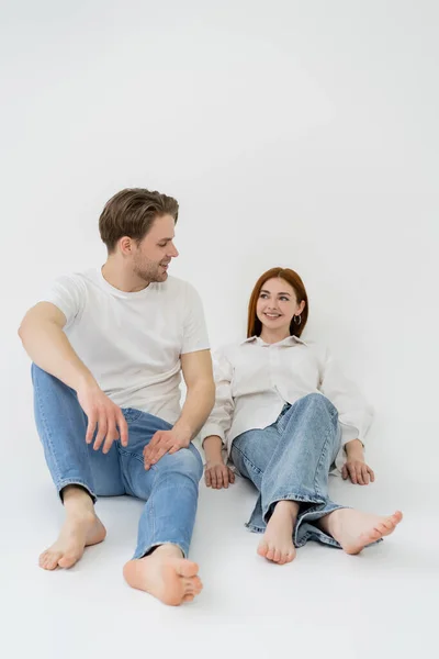 Positive barefoot couple sitting on white background — Stock Photo