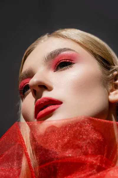 Vista de ángulo bajo de la mujer con rostro rojo y tela mirando hacia otro lado aislado en gris - foto de stock