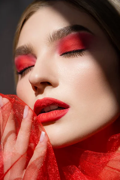 Portrait of woman with red visage holding tulle cloth isolated on grey — Stock Photo