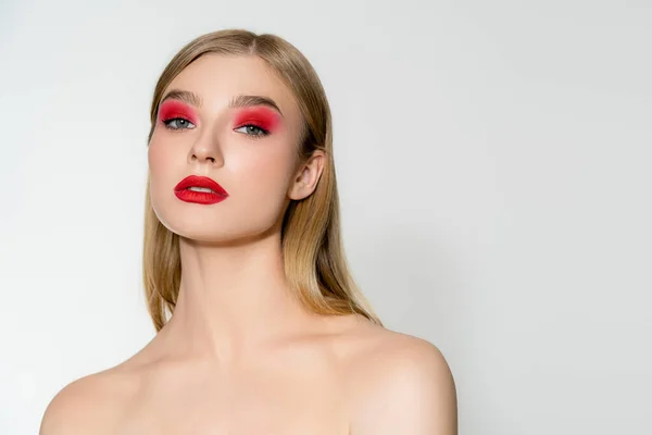 Young woman with naked shoulders and red lips looking at camera isolated on grey — Stock Photo