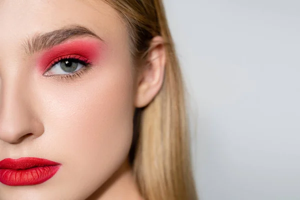 Vista recortada de la mujer con maquillaje rojo mirando a la cámara aislada en gris - foto de stock