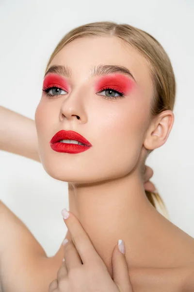 Young model with red visage touching neck isolated on grey — стоковое фото