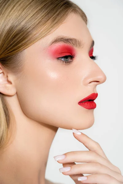 Young woman with red lips and eye shadow looking away isolated on grey — Stock Photo