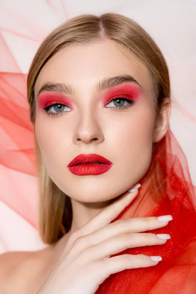 Junge Frau mit rotem Make-up hält Tuch in der Hand und blickt in die Kamera auf grauem Hintergrund — Stockfoto
