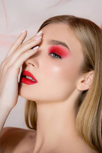 Modelo joven con cara cubierta de rostro rojo cerca de tela sobre fondo gris - foto de stock