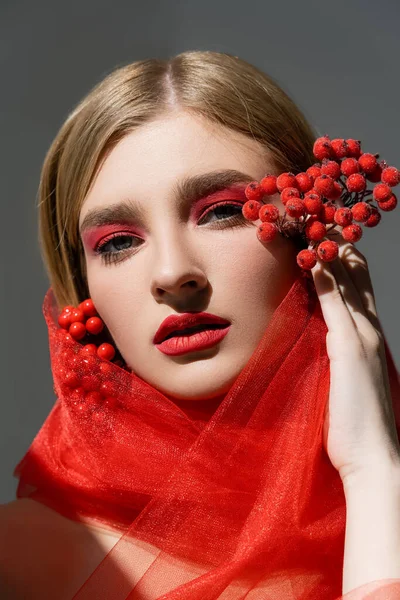 Portrait of woman with red makeup and cloth holding berries isolated on grey — Stock Photo