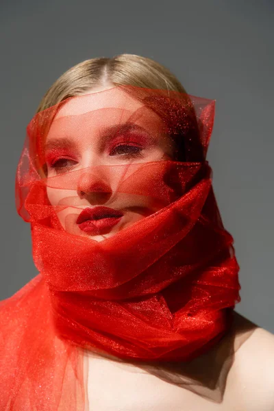 Femme aux lèvres rouges enveloppée dans un tissu en tulle isolé sur gris — Photo de stock