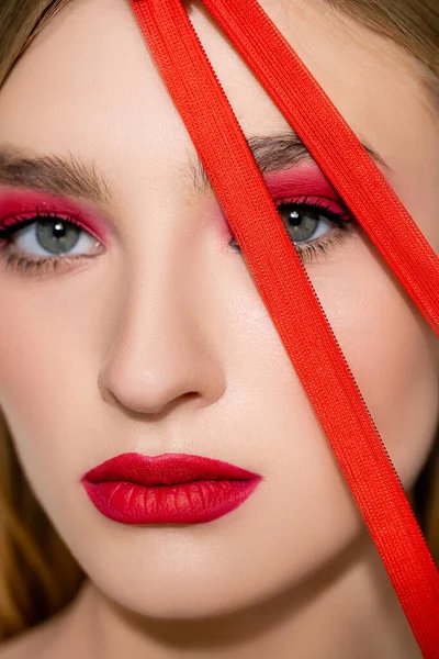 Close up view of model with red makeup looking at camera near zipper — стоковое фото