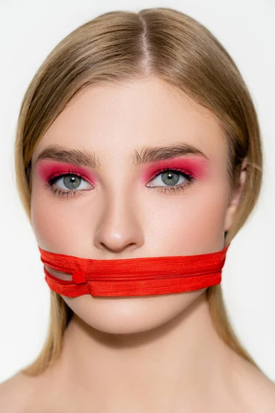 Junge Frau mit rotem Lidschatten und Reißverschluss am Mund blickt vereinzelt auf graue Kamera — Stockfoto