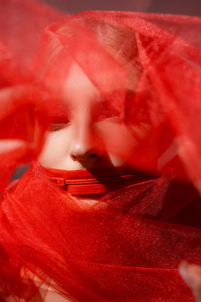 Jeune femme avec fermeture éclair sur la bouche et tissu rouge flou sur fond gris — Photo de stock