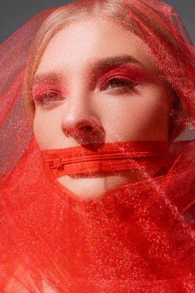 Young woman in tulle cloth and red zipper on mouth isolated on grey — стоковое фото