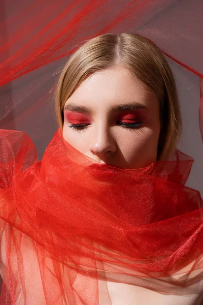 Jeune modèle blonde en tissu rouge sur fond gris — Photo de stock