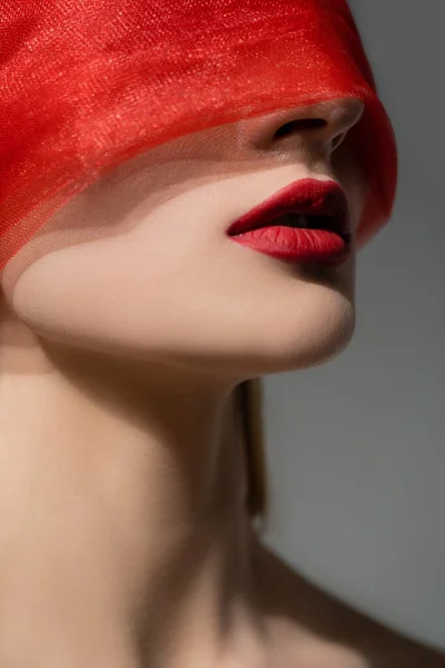 Жінка з червоними губами і тканиною на обличчі позує ізольовано на сірому — стокове фото