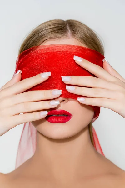 Femme avec maquillage rouge toucher tissu sur le visage isolé sur gris — Photo de stock