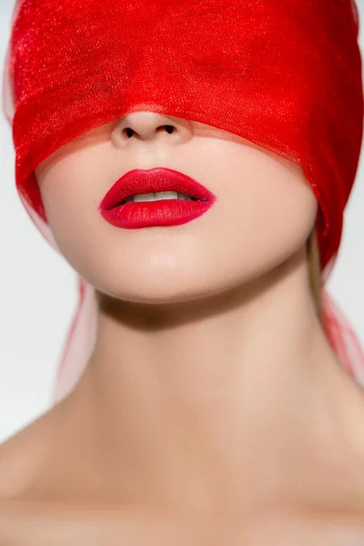 Jeune femme avec lèvres rouges et tissu sur le visage isolé sur gris — Photo de stock