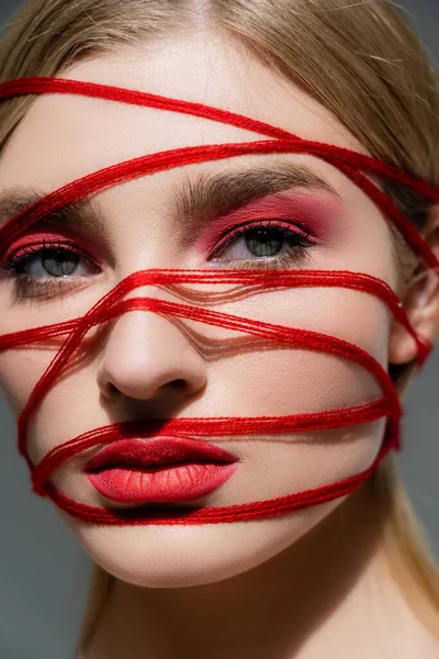 Ritratto di giovane modella con labbra e fili sul viso guardando la fotocamera isolata su grigio — Foto stock