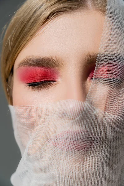 Close up view of woman with red eye shadow and medical bandage on face isolated on grey — Stock Photo