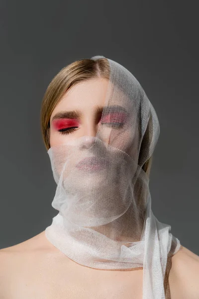 Young woman with red visage and medical bandage on face isolated on grey — стоковое фото