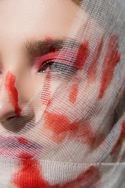 Cropped view of woman with red print of hand on medical bandage on face looking away — Stock Photo