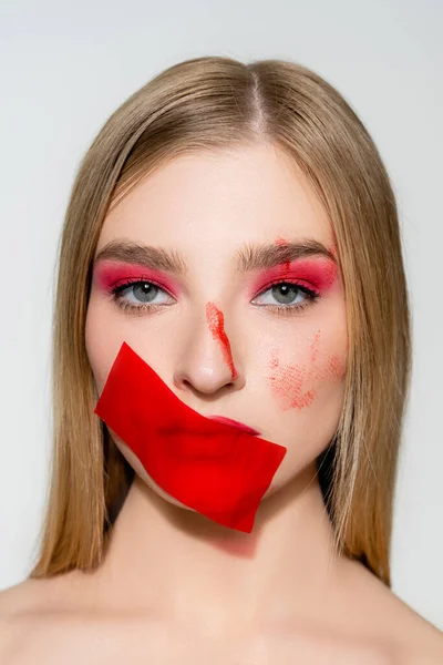 Portrait de femme avec visage rouge et ruban adhésif sur la bouche isolé sur gris — Photo de stock