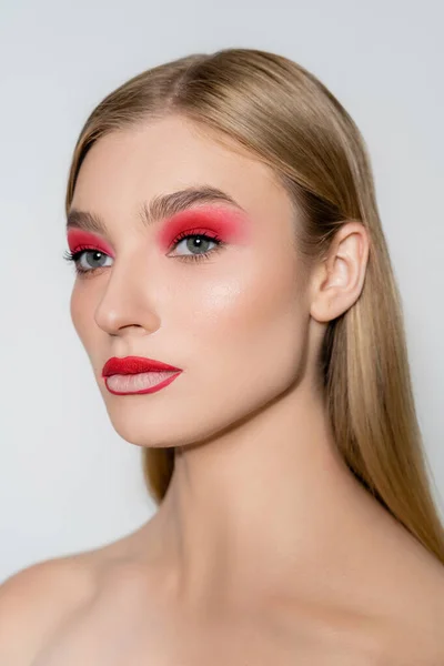 Jeune modèle avec épaule nue et maquillage rouge regardant loin isolé sur gris — Photo de stock