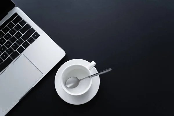 Top view of laptop near empty cup with spoon on black — Fotografia de Stock