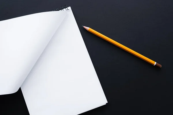 Top view of blank notebook and pencil on black — Stock Photo