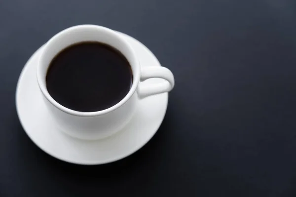 Top view of aromatic cup of coffee with saucer on black — Foto stock