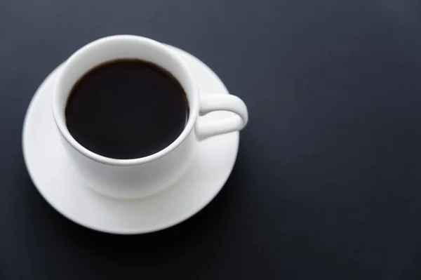 Top view of aromatic cup of coffee with saucer on black — Fotografia de Stock