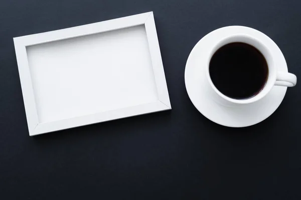 Top view of frame near cup of coffee on black — Stockfoto