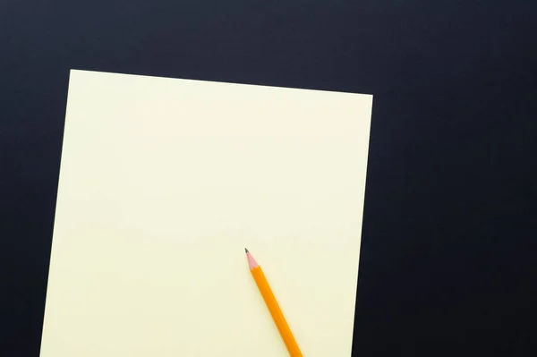Top view of blank pastel color paper with pencil on black — Fotografia de Stock