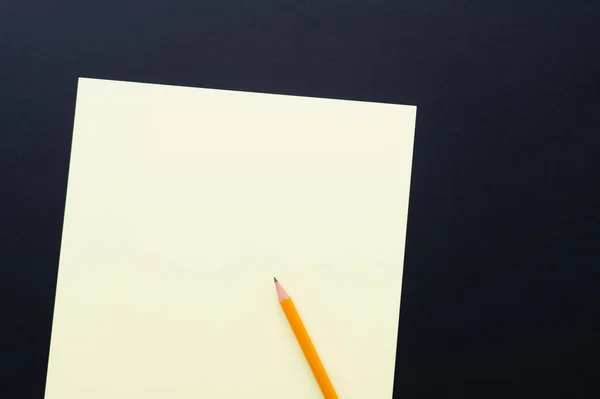 Vue du dessus du papier blanc de couleur pastel avec crayon sur noir — Photo de stock