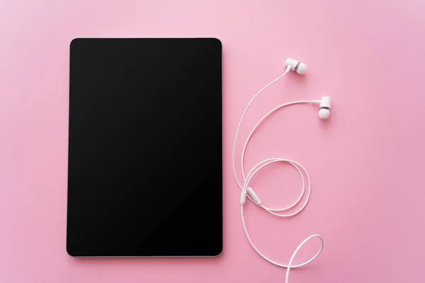 Ansicht von oben digitales Tablet mit leerem Bildschirm in der Nähe von verdrahteten Kopfhörern auf rosa — Stockfoto