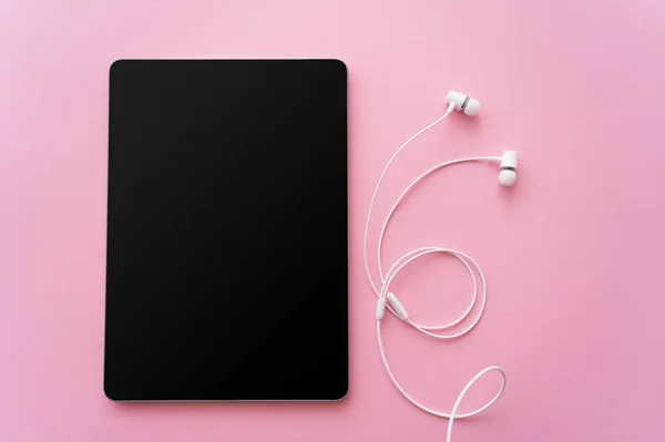 Top view of digital tablet with blank screen near wired earphones on pink — Stock Photo