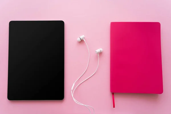 Top view of digital tablet with blank screen near earphones and bright notebook on pink — Stock Photo