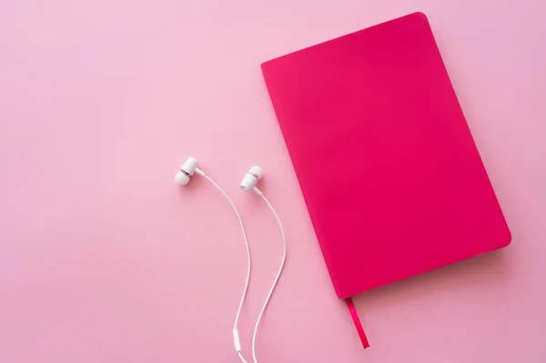 Kopfhörer in der Nähe heller Notebooks auf rosa — Stockfoto