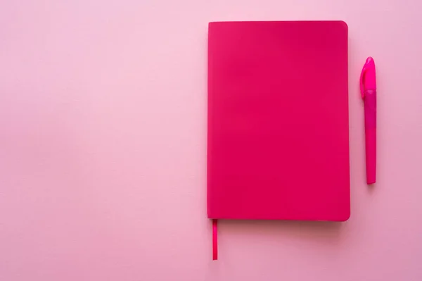 Top view of bright notebook and pen on pink — стоковое фото
