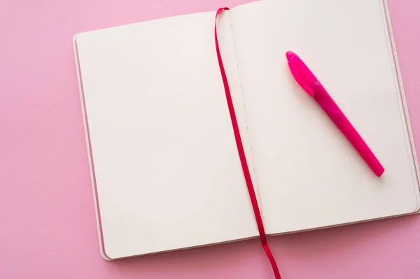 Top view of empty open notebook and pen on pink — Foto stock
