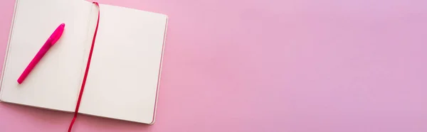 Vista superior del cuaderno abierto vacío y la pluma en rosa, bandera - foto de stock