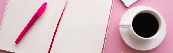 Вид зверху ручки на відкритому ноутбуці біля чашки кави та ноутбука на рожевому, банер — стокове фото