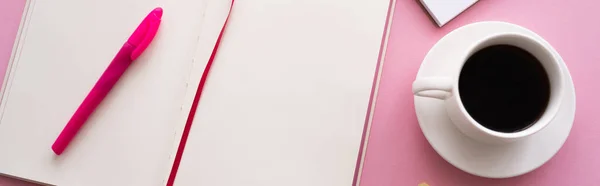 Top view of pen on open notebook near cup of coffee and notebook on pink, banner — Stock Photo