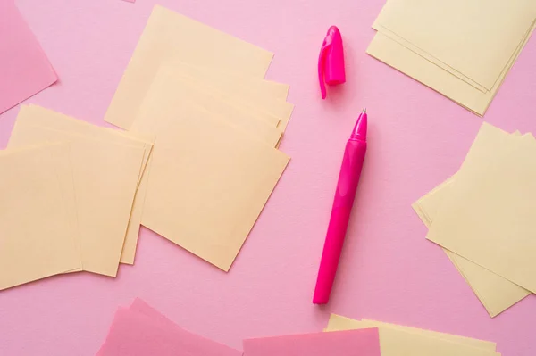 Vista superior de notas de papel pastel vazias perto de caneta brilhante em rosa — Fotografia de Stock