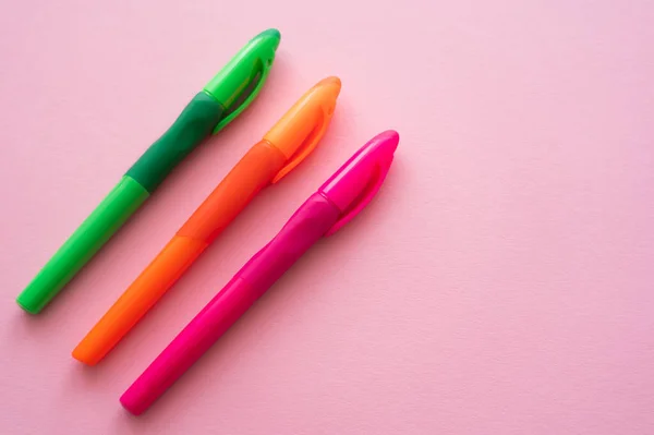 Vue de dessus des stylos colorés et lumineux sur rose — Photo de stock