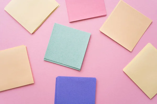 Vue du haut des notes en papier colorées et vierges sur rose — Photo de stock