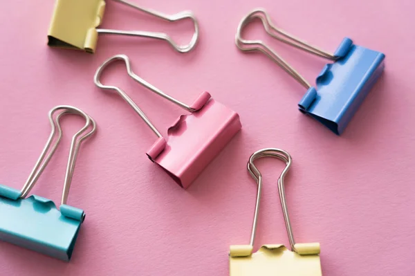 Close up of colorful pastel fold back clips on pink — Stock Photo