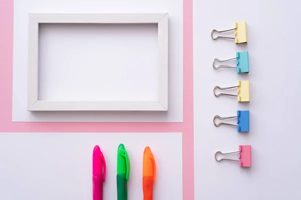 Top view of colorful stationery near blank frame and papers on pink — Foto stock