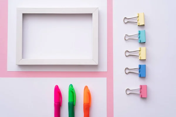 Top view of colorful stationery near blank frame and papers on pink — стоковое фото