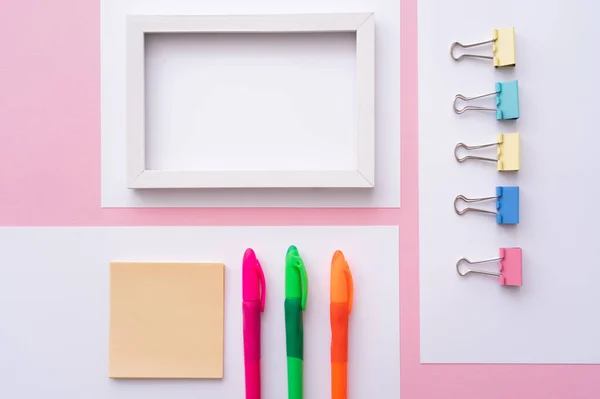 Leigos planos de artigos de papelaria coloridos perto de moldura em branco e papéis em rosa — Fotografia de Stock