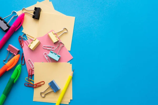 Top view of colorful paper clips and fold back clips on paper notes on black — Stock Photo